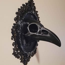 Decorative black bird beak mask with ornate frame on a beige background