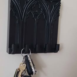 Black decorative key holder with keys attached on a white wall