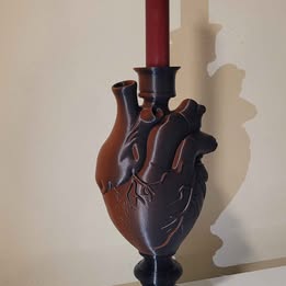 Heart-shaped candle holder with a red candle on a beige background