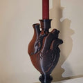 Heart-shaped candle holder with a red candle on a beige background