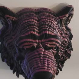 Decorative wall sculpture of a bear head with purple and black colors on a plain background