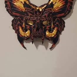 Decorative wall art in the shape of a butterfly with a fiery design on a plain background