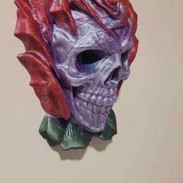 Decorative skull wall piece with red and purple accents on a beige background