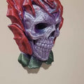 Decorative skull wall piece with red and purple accents on a beige background