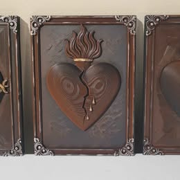 Decorative wall art with a heart design and flame on a deep red background