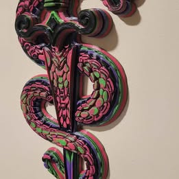 Colorful snake-shaped object with intricate patterns on a beige background