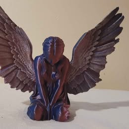 Statue of an angel with outstretched wings on a white surface