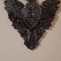 Decorative wall piece with winged black bird design on a beige background
